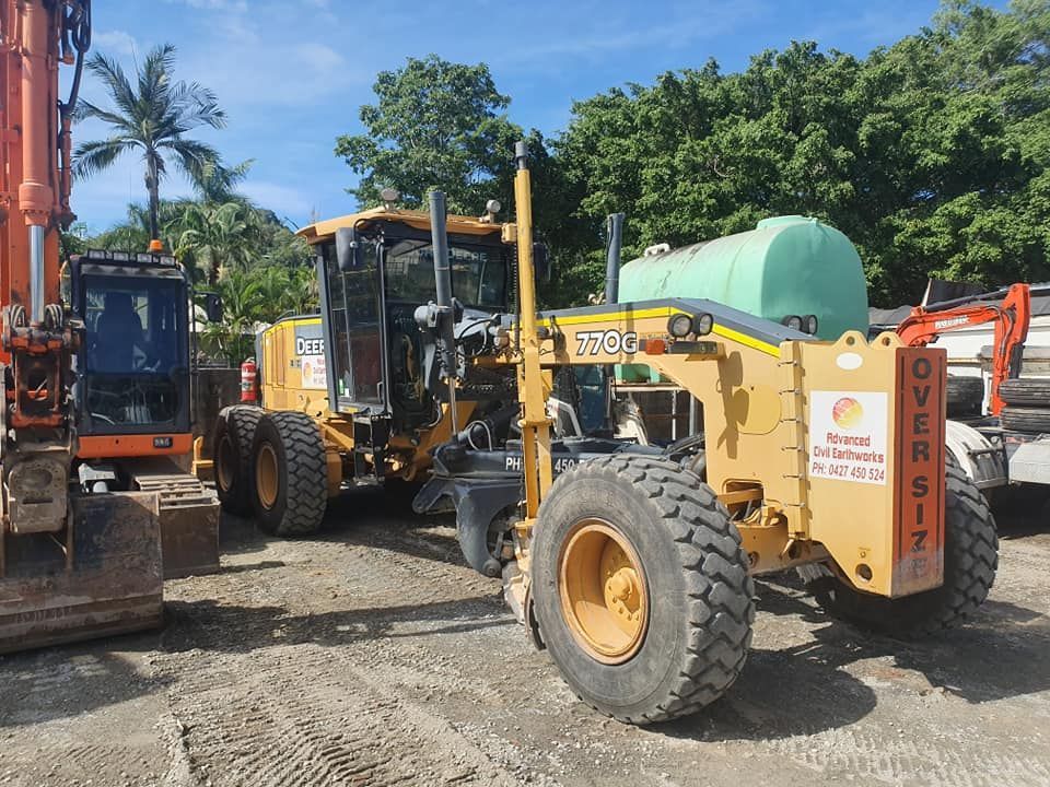 A Large Yellow Tractor With a Green Tank on the Back is Parked in a Dirt Lot — Advanced Civil Earthworks In Koah, QLD