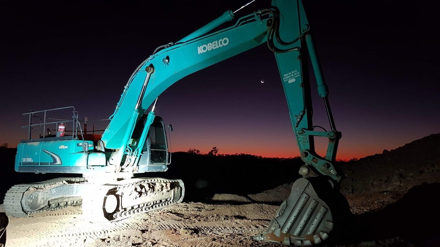 A Large Excavator is Parked in a Dirt Field at Night — Advanced Civil Earthworks In Cape York, QLD