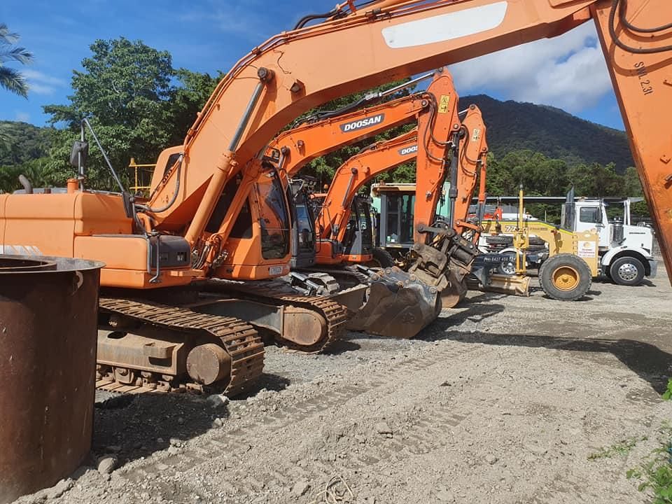 A Group of Orange Excavators Are Parked in a Dirt Lot — Advanced Civil Earthworks In Cape York, QLD