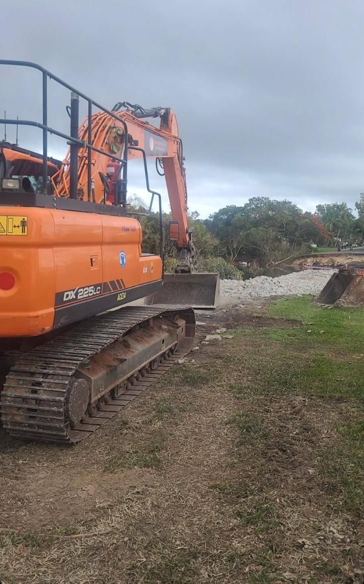 A Large Orange Excavator is Sitting on Top of a Dirt Field — Advanced Civil Earthworks In Mount Isa, QLD