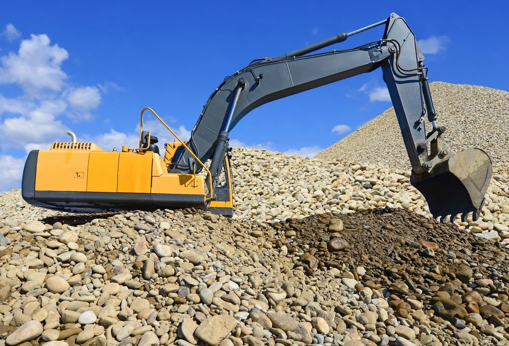 A Yellow and Gray Excavator is Digging in a Pile of Rocks — Advanced Civil Earthworks In Cooktown, QLD