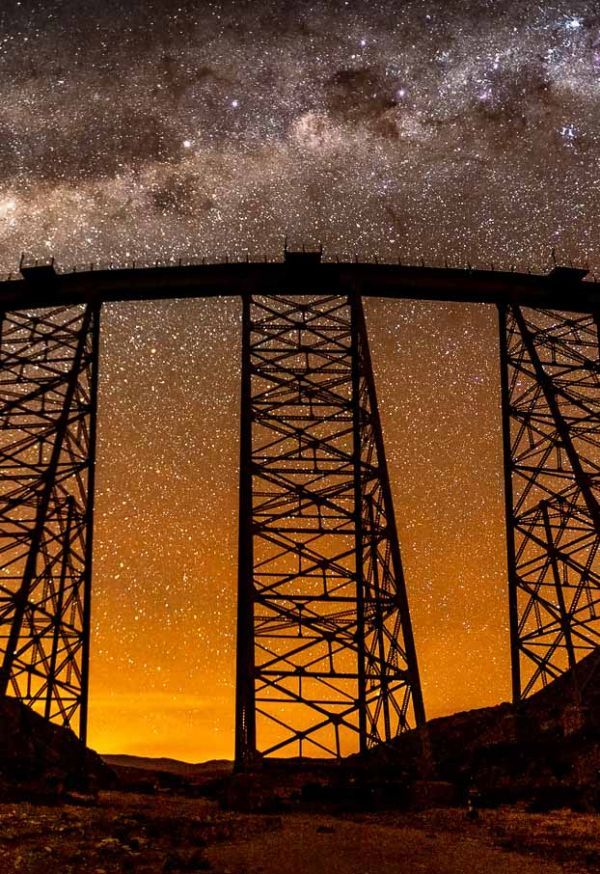 A bridge is silhouetted against a starry night sky