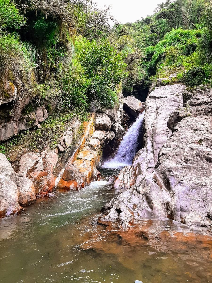 A waterfall is coming down a rocky cliff into a river.