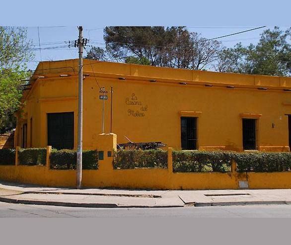 A yellow building with a fence and trees in the background