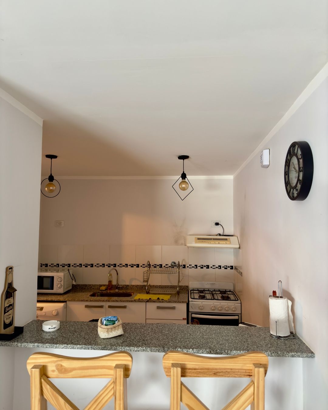 A kitchen with a clock on the wall above the stove