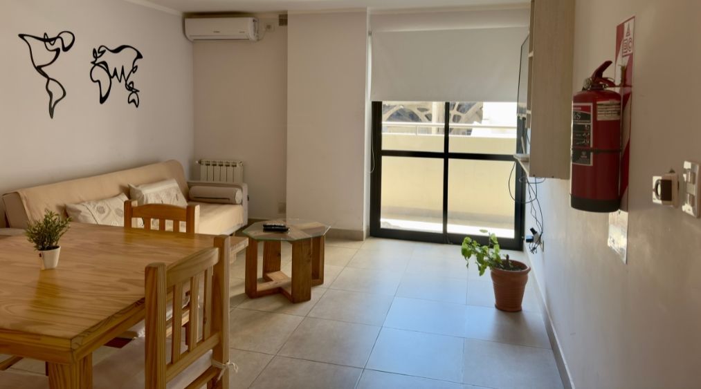 A living room with a table and chairs and a fire extinguisher on the wall.
