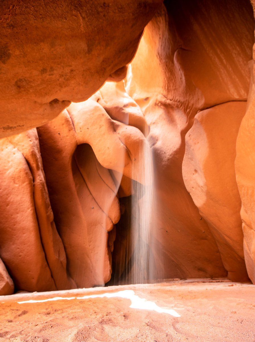 A waterfall is coming out of a cave in the desert.