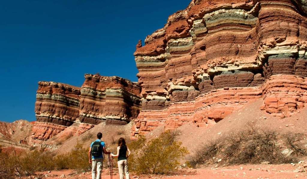A man and a woman are standing in front of a rock formation