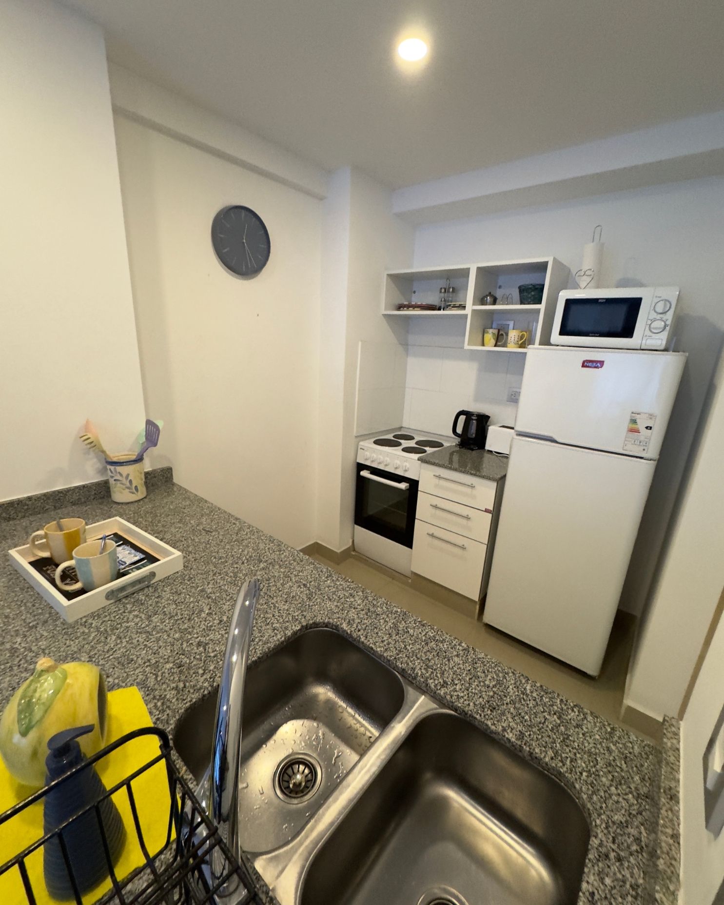 A kitchen with a sink , refrigerator , microwave and stove.