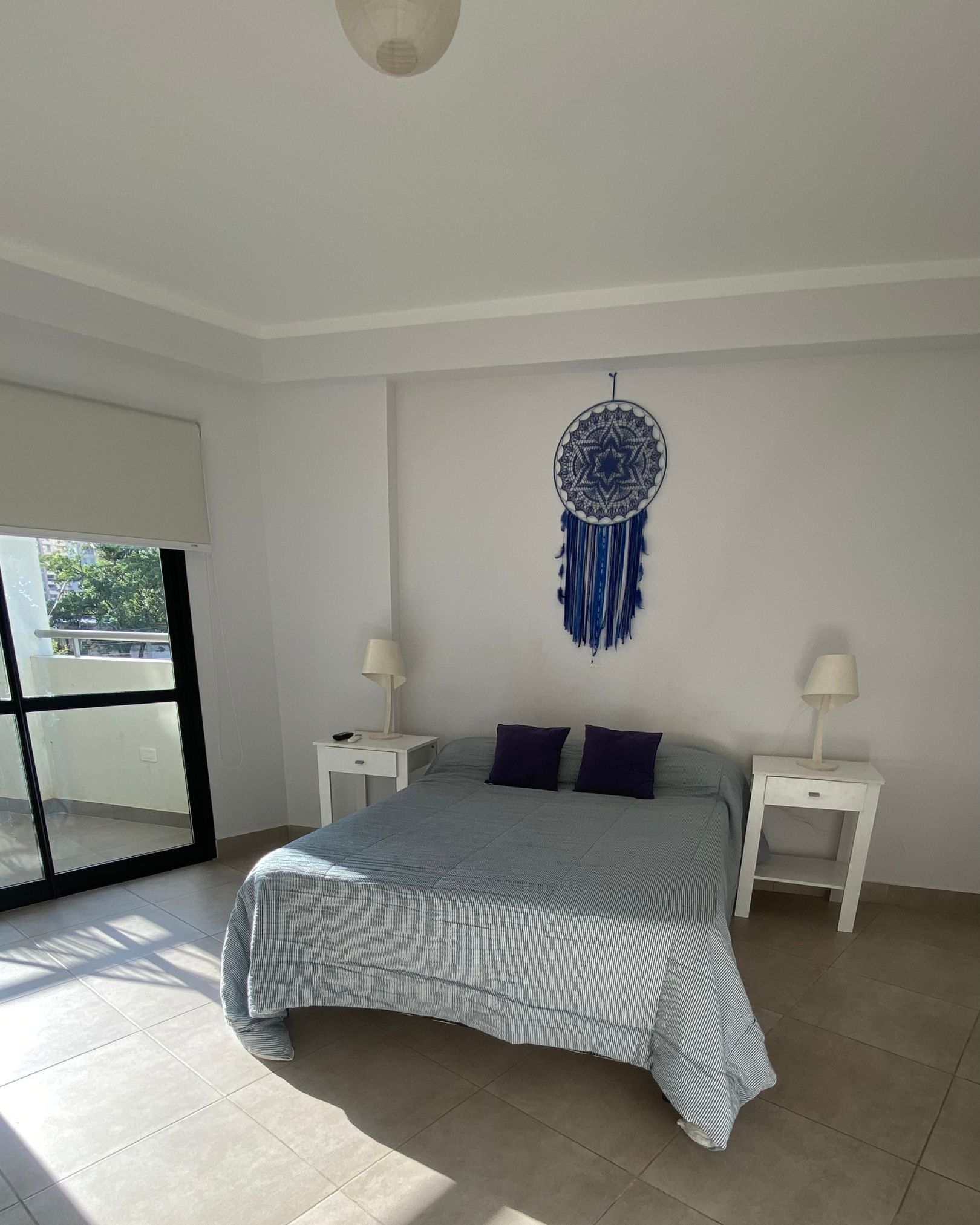 A bedroom with a bed and a dream catcher on the wall.