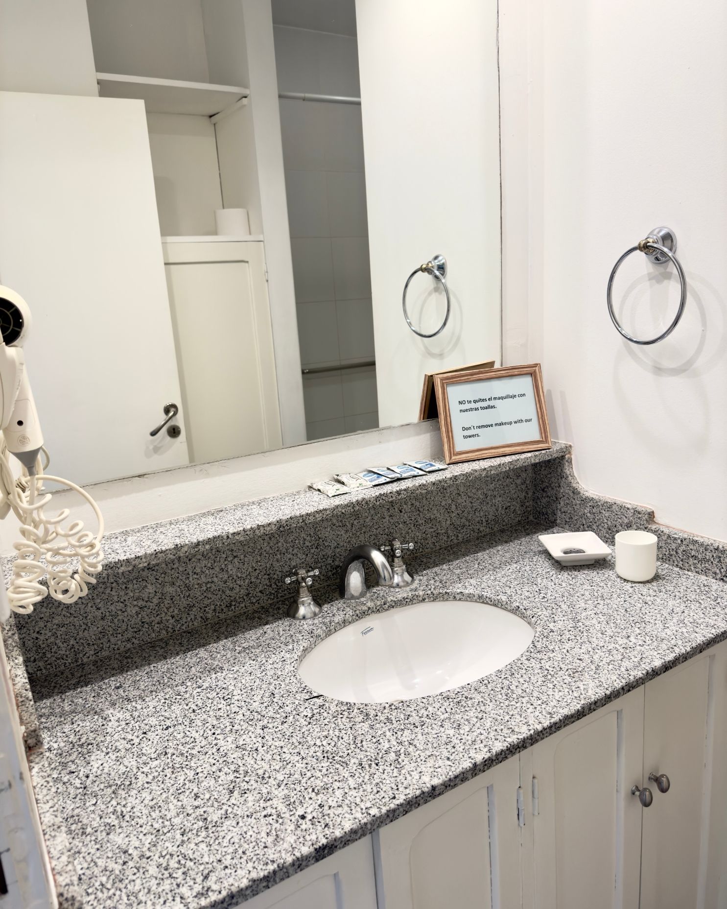A bathroom with a sink , mirror and hair dryer