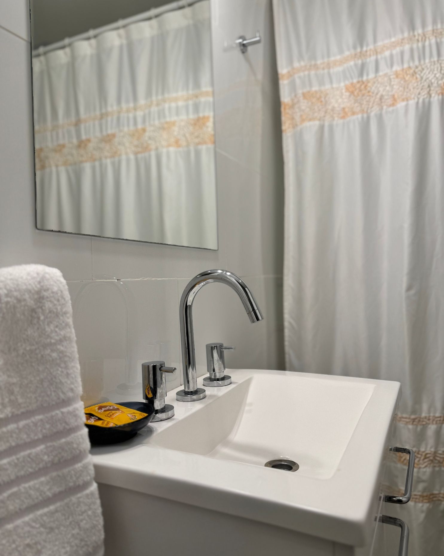 A bathroom with a sink a mirror and a shower curtain