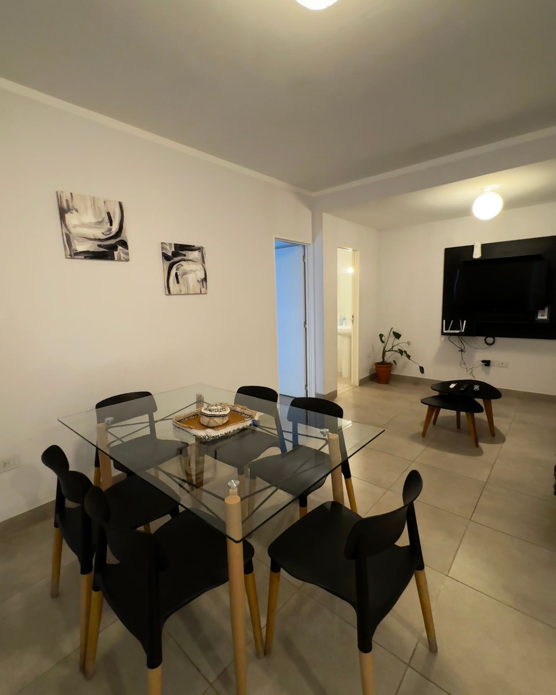 A dining room with a glass table and black chairs