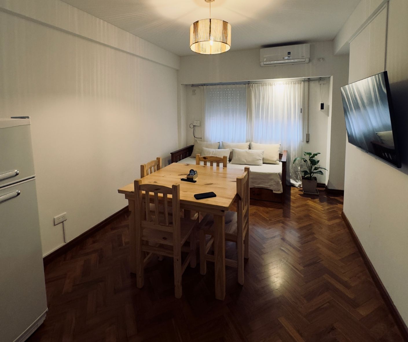 A living room with a dining table and chairs and a flat screen tv.