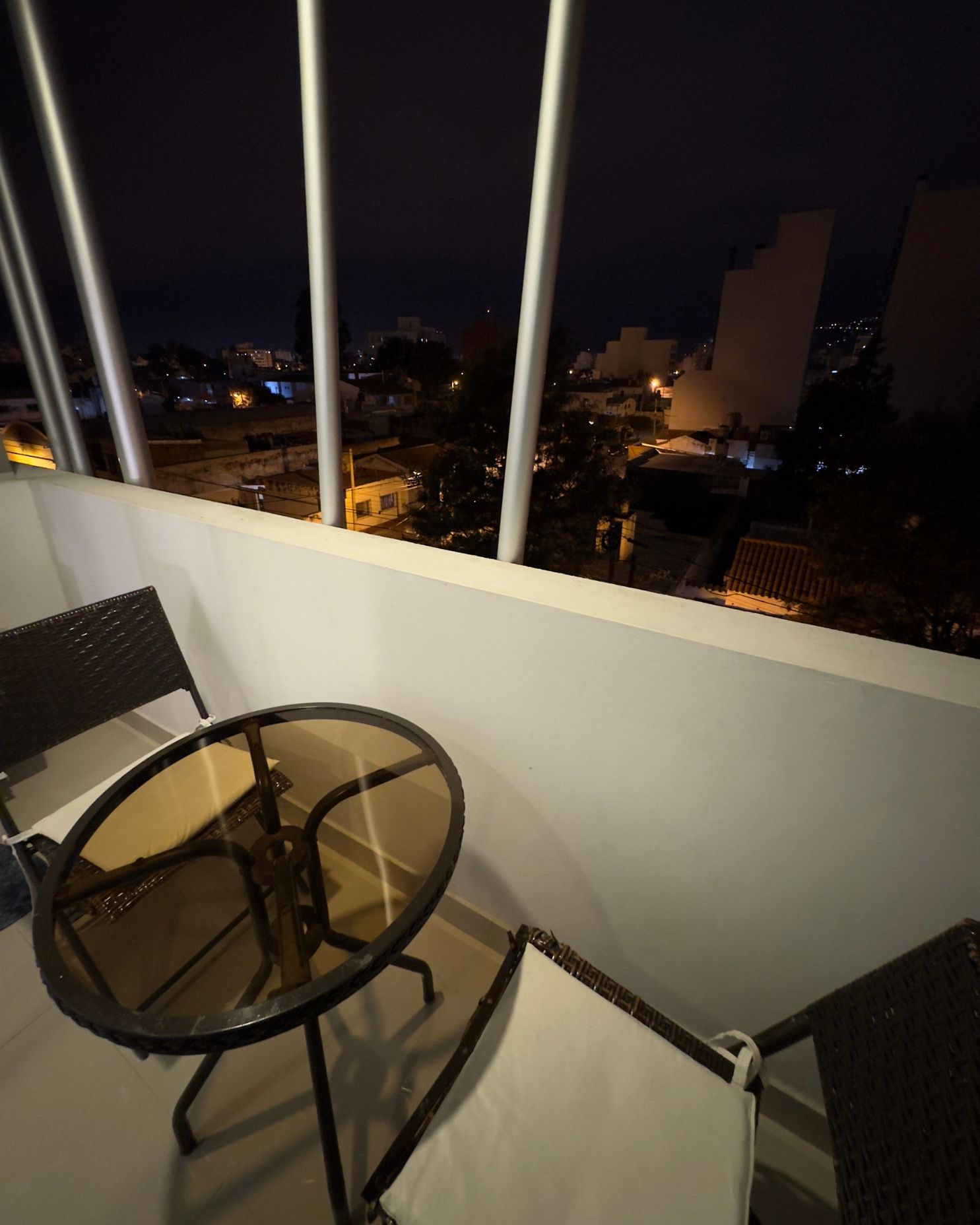 A balcony with a table and chairs at night