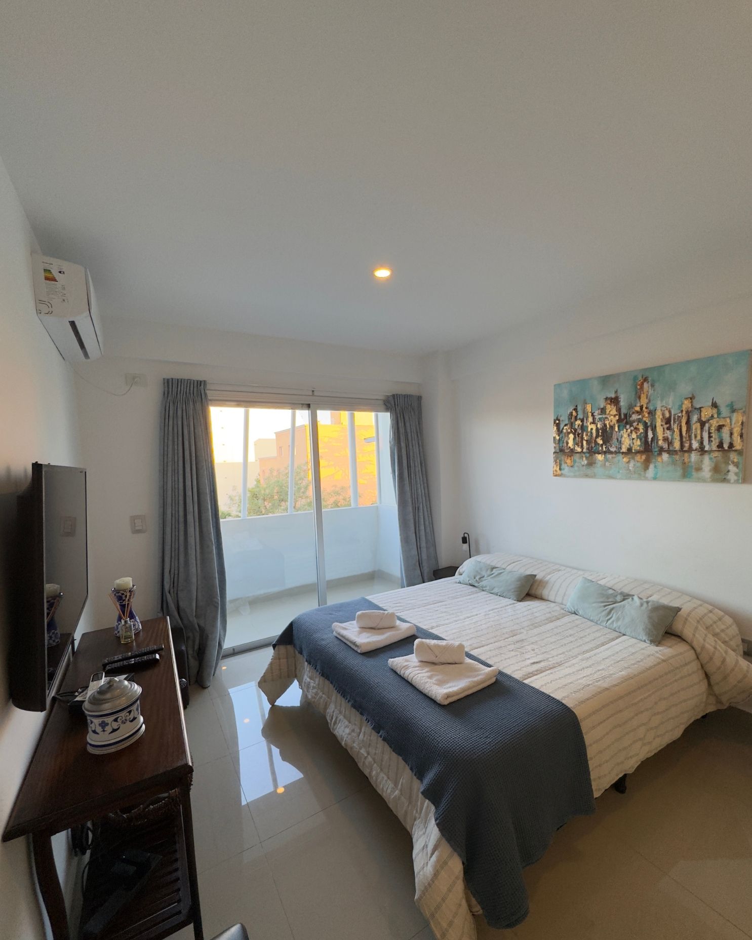 A bedroom with two beds , a television , and a balcony.