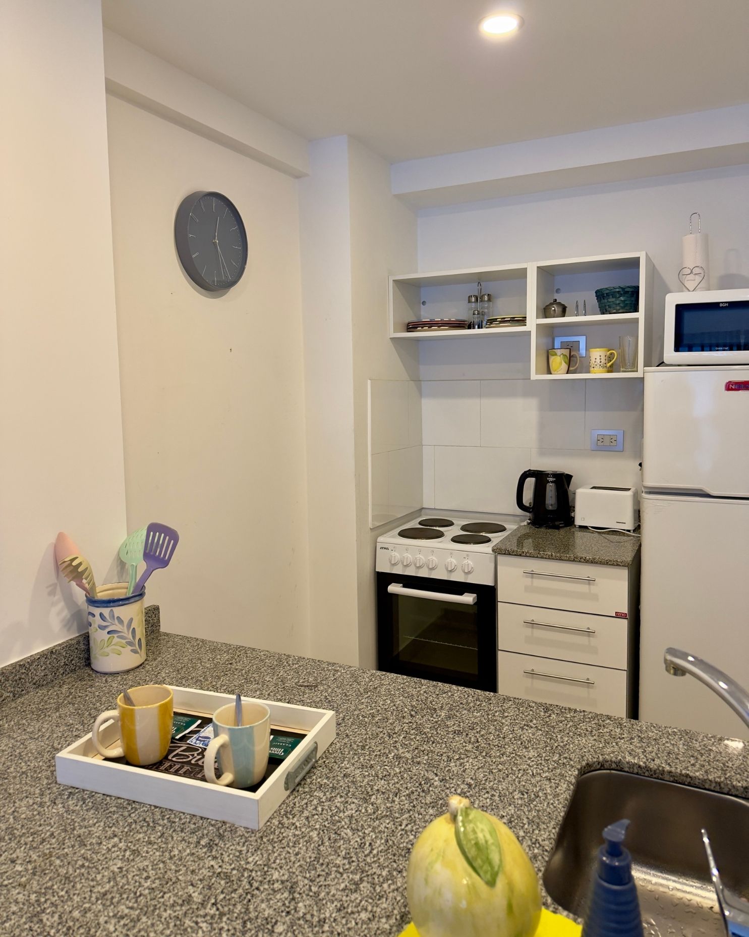 A kitchen with a clock on the wall above the counter