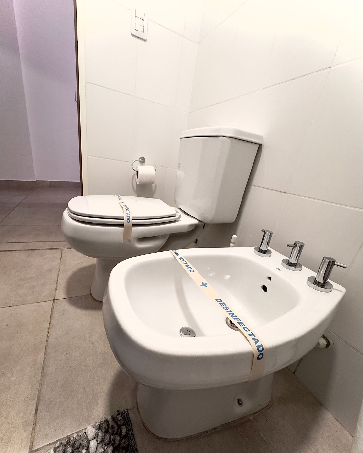 A bathroom with a toilet and a bidet with a tape on it