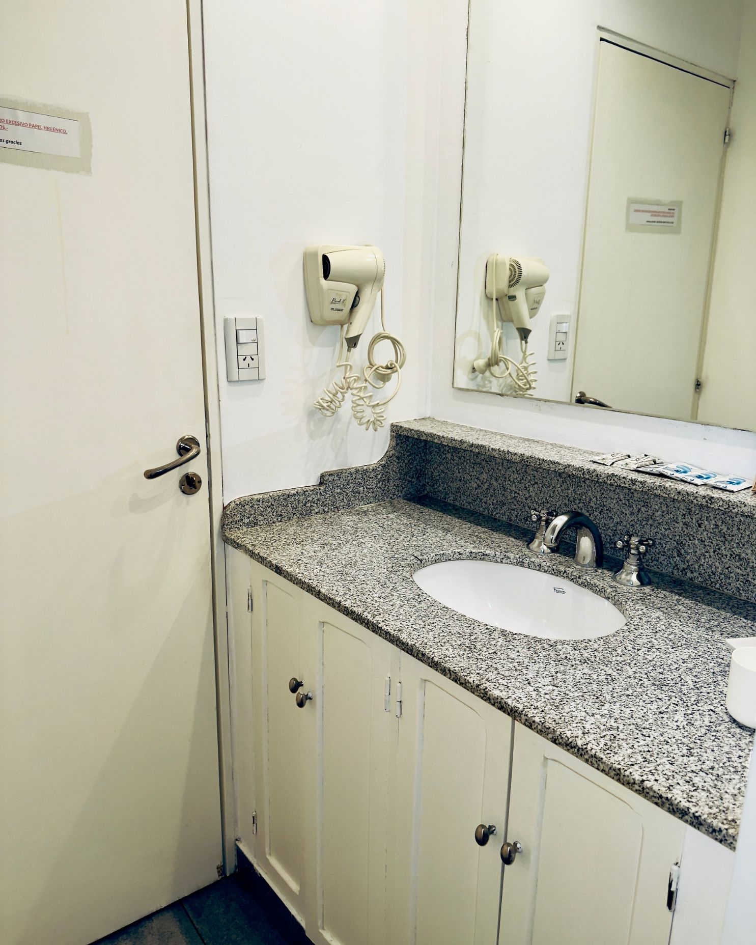 A bathroom with a sink a mirror and a hair dryer