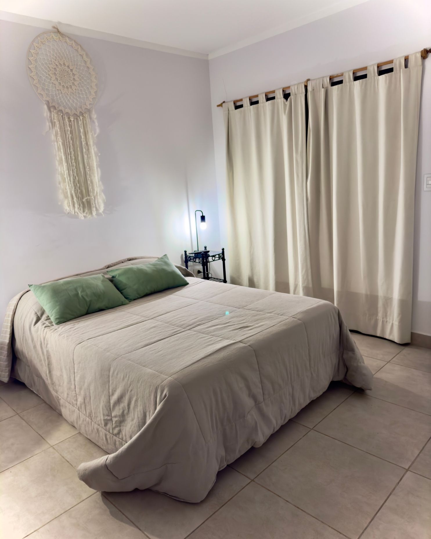 A bedroom with a bed and a dream catcher on the wall