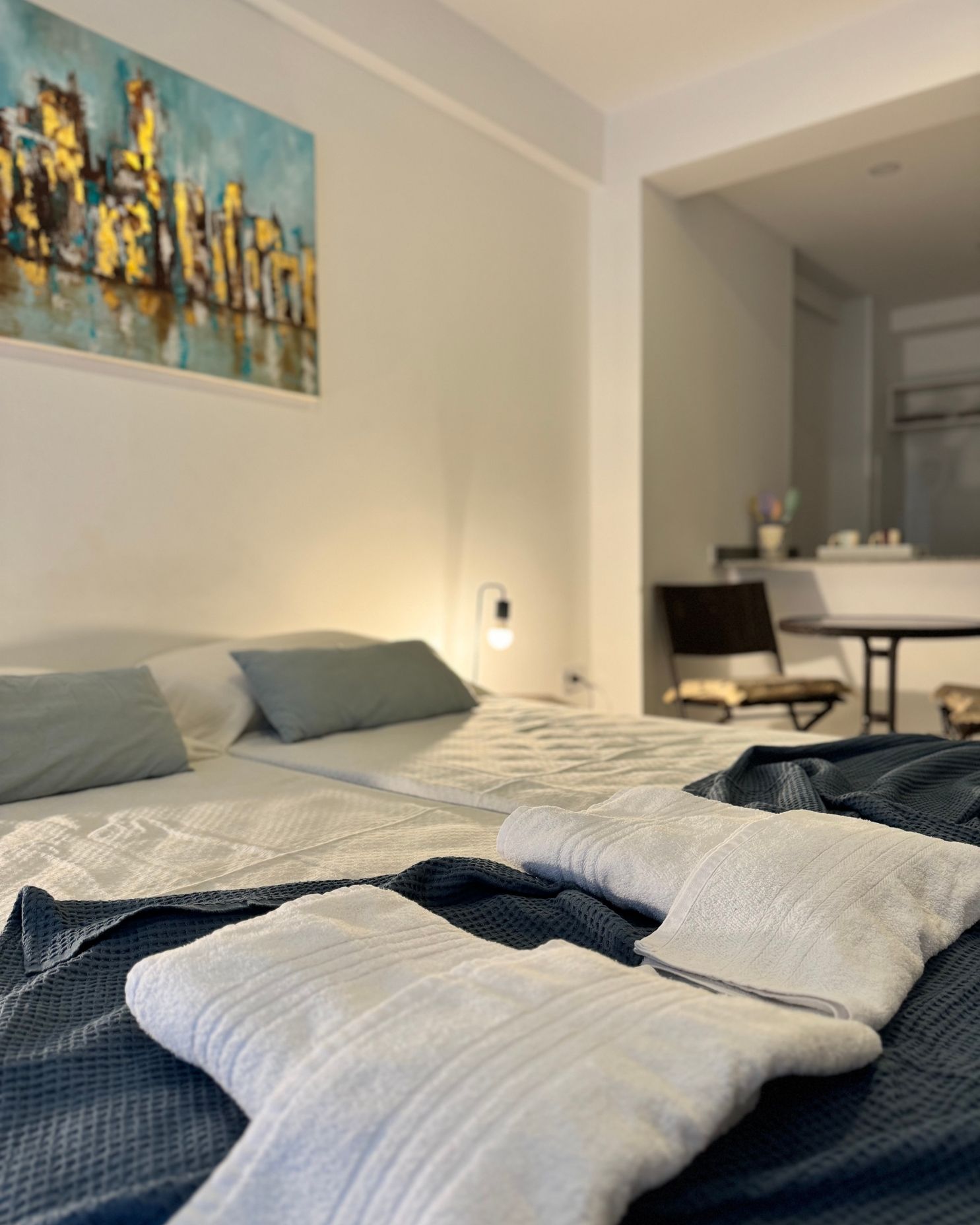 A bedroom with two beds and a painting on the wall