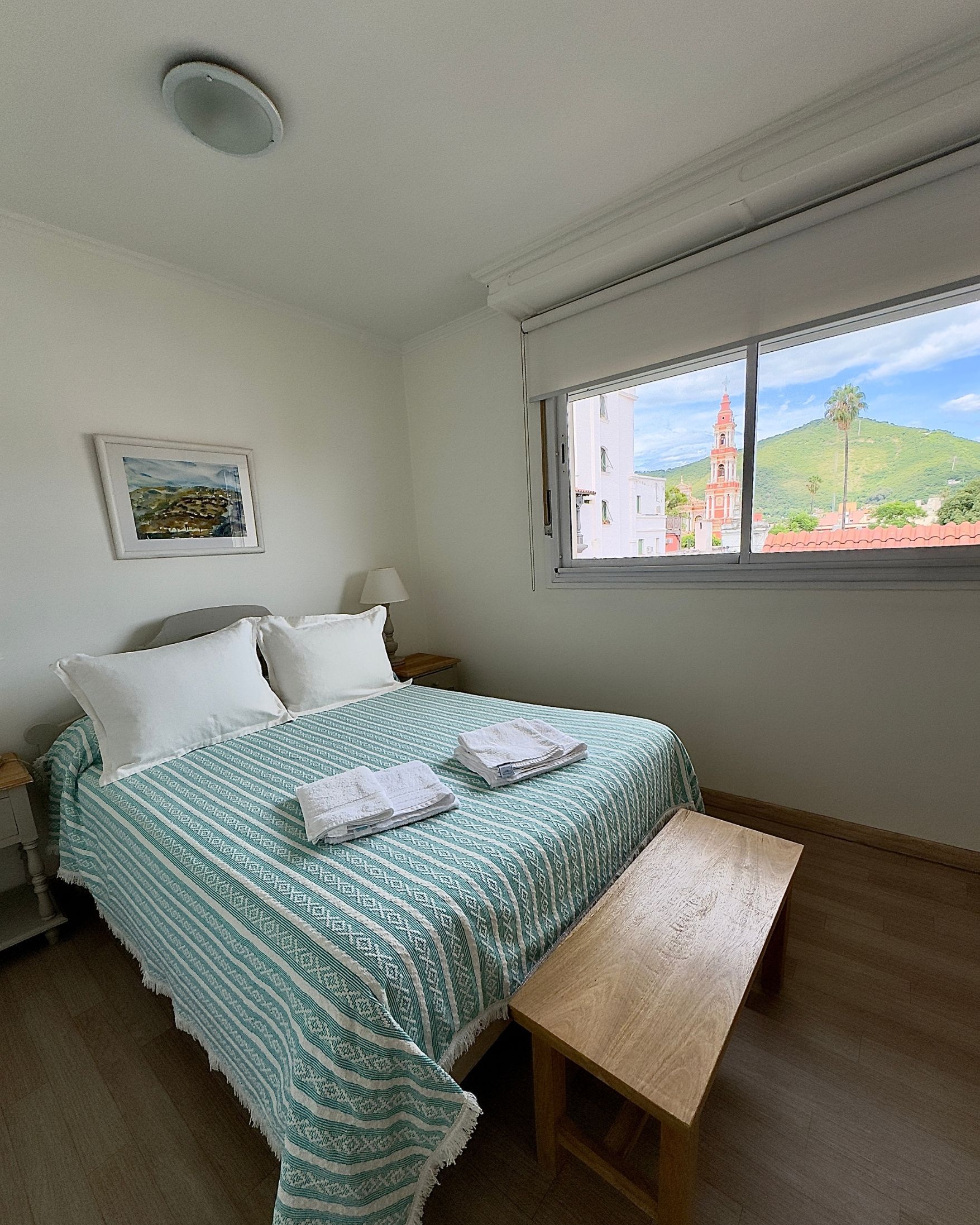 A bedroom with a bed and a bench in front of a window.