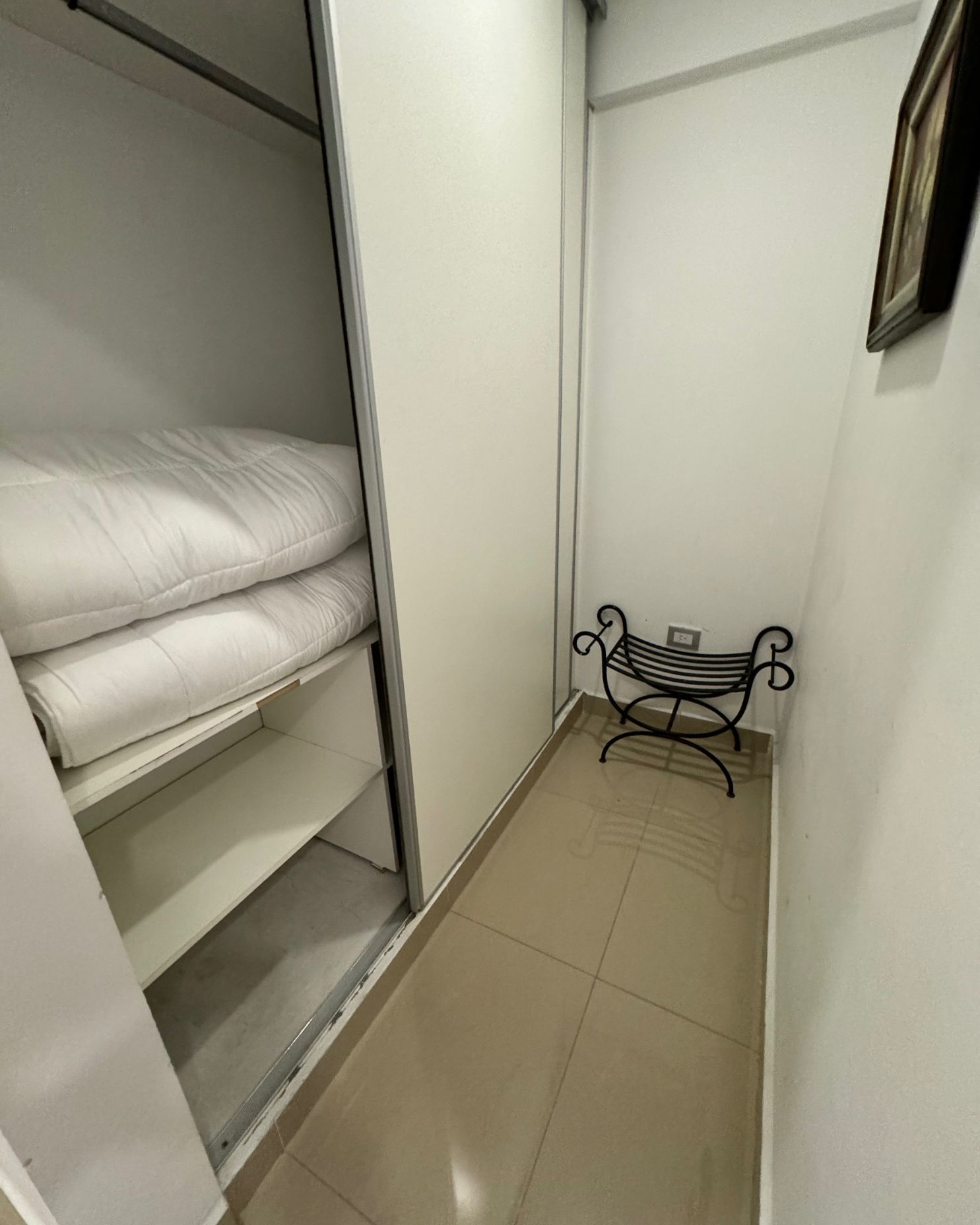A closet with a bench and a picture on the wall.