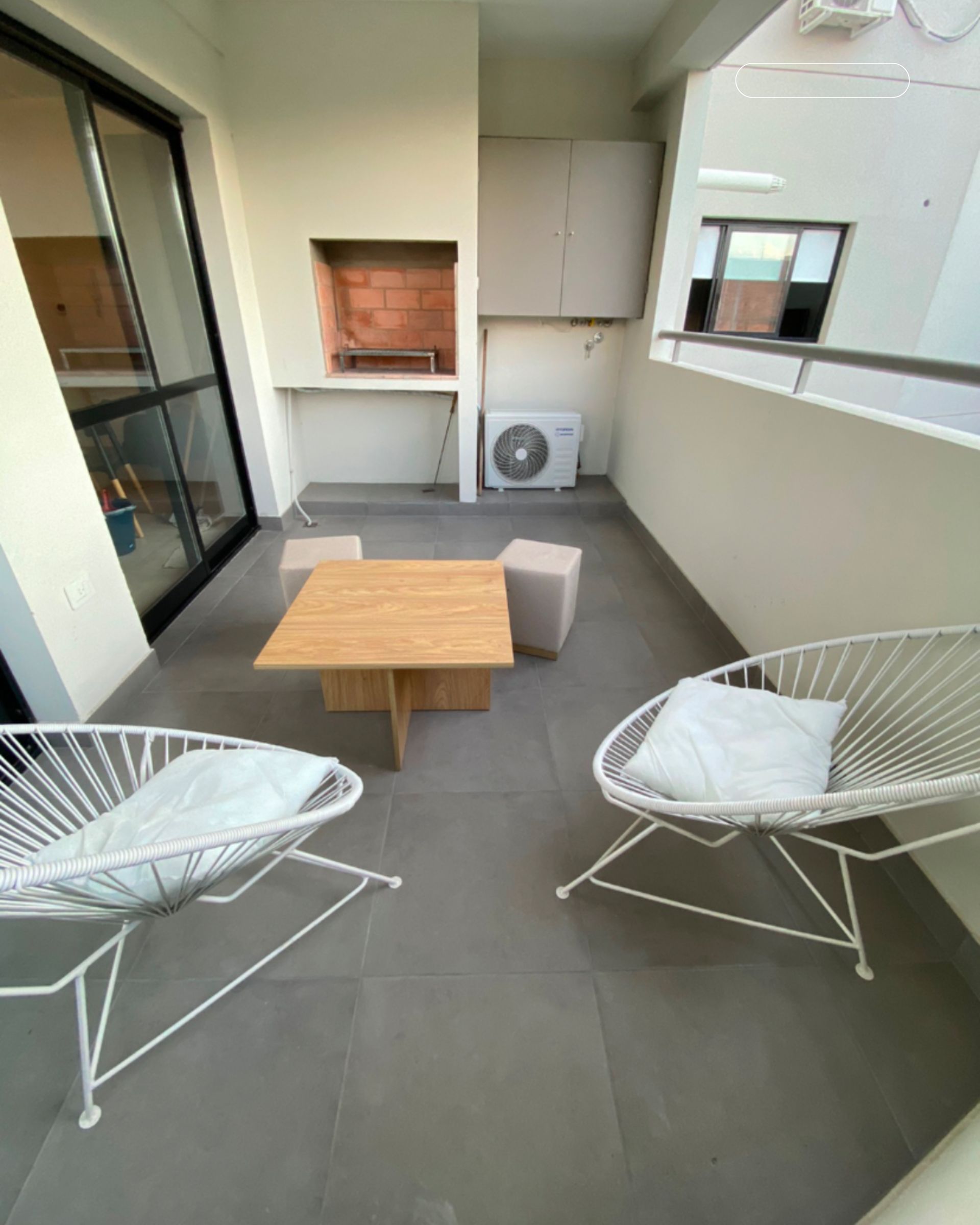 There are two chairs and a table on the balcony.