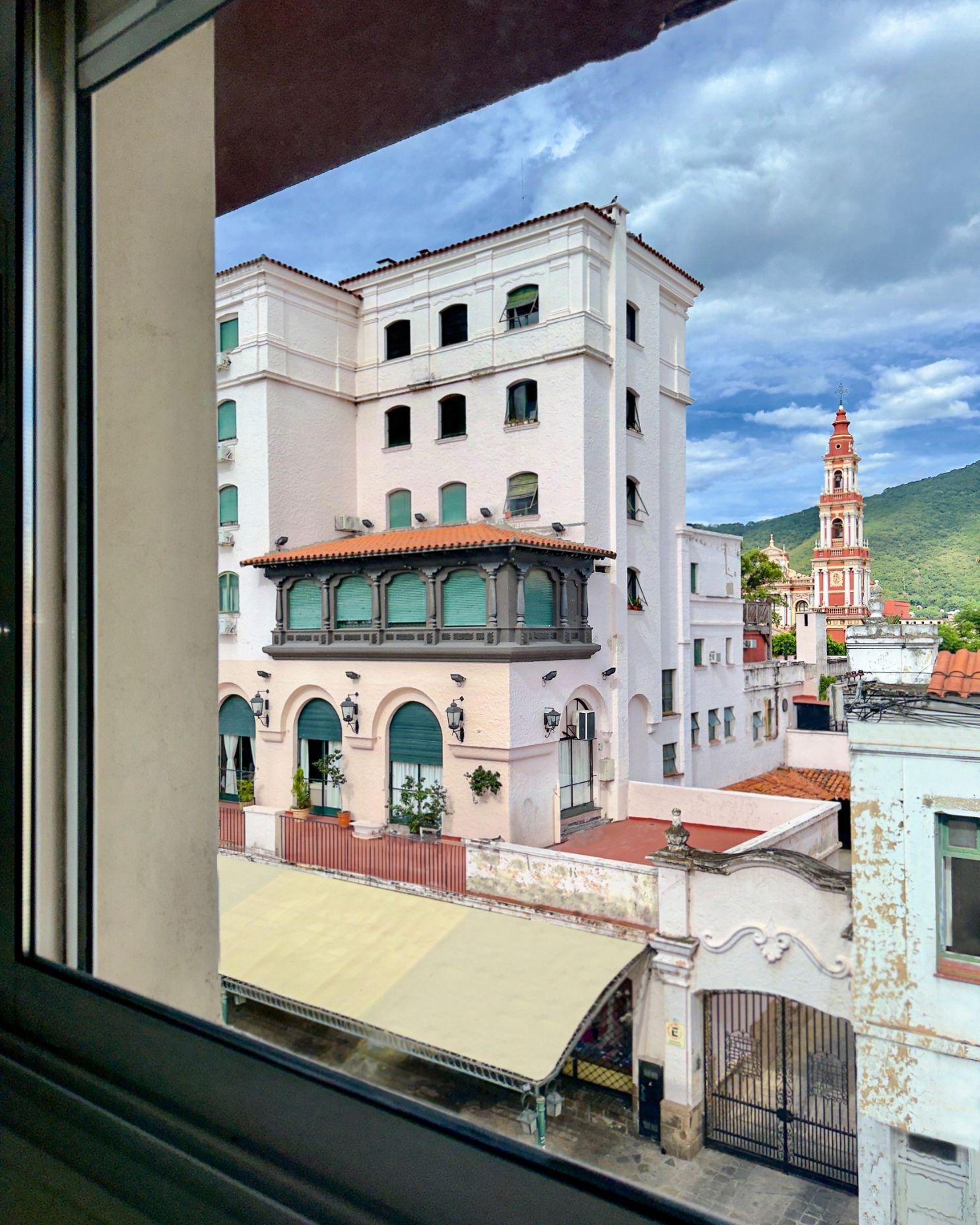 A view of a building from a window with a clock tower in the background