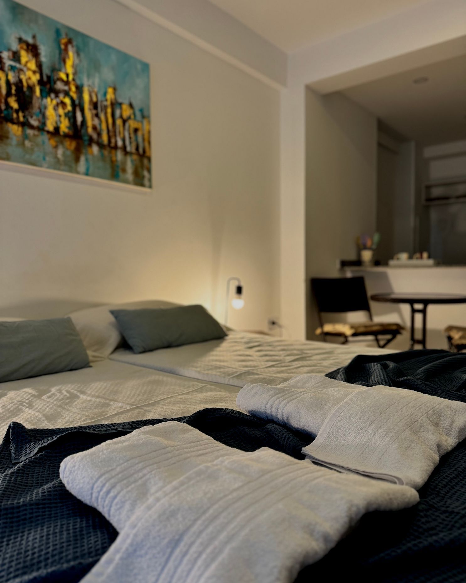 A bedroom with a painting on the wall above the bed