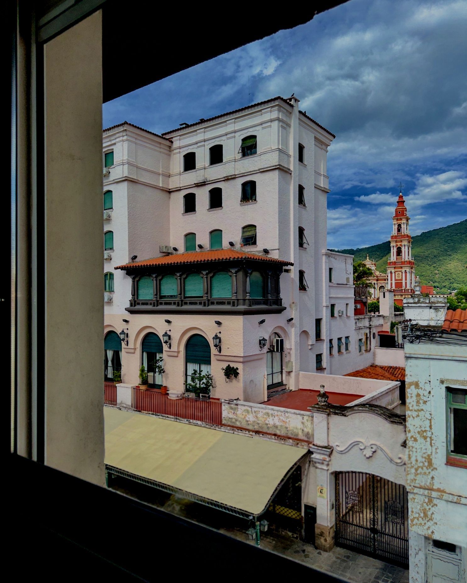 A view of a building from a window with a clock tower in the background