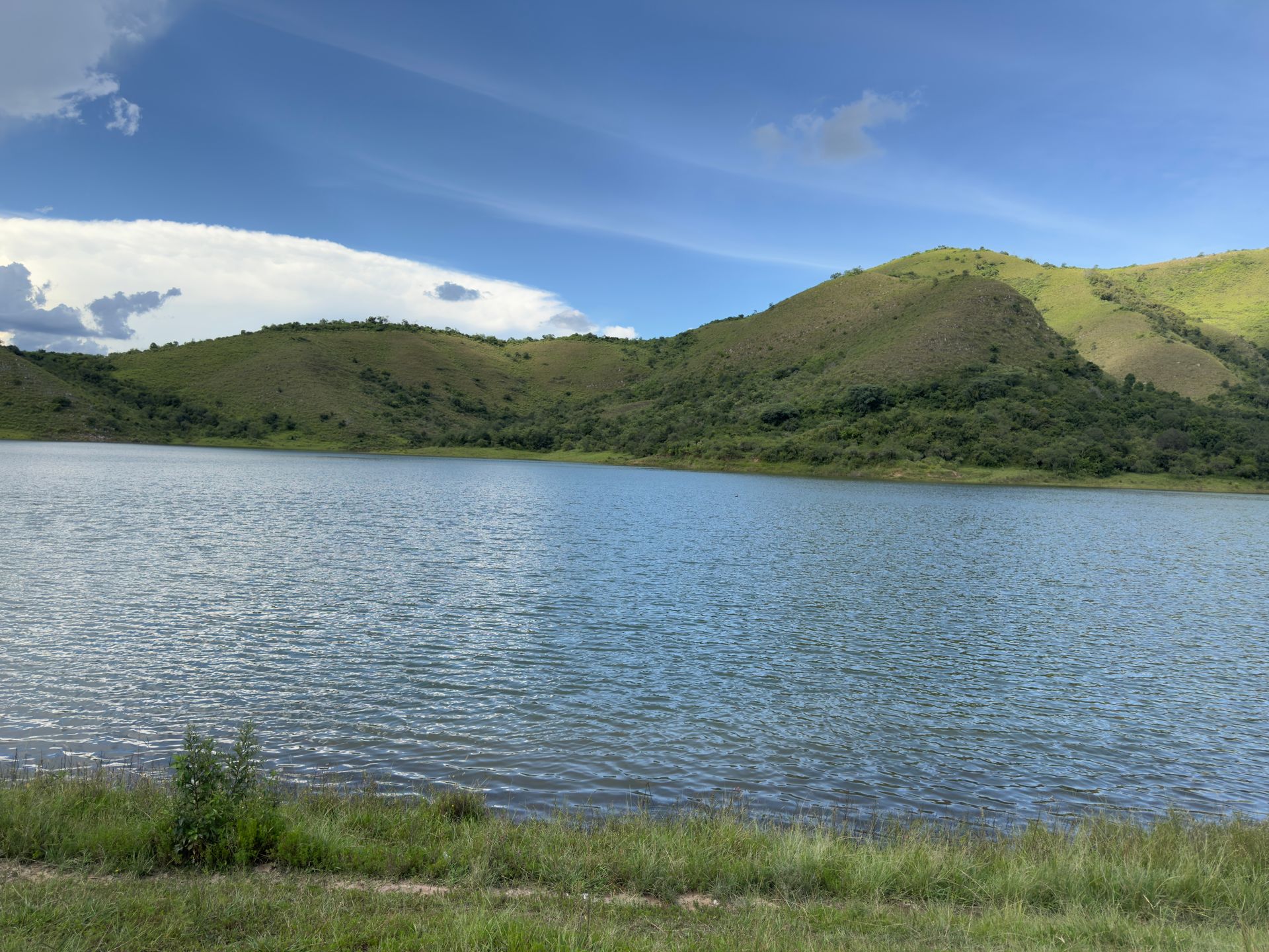 A large body of water surrounded by mountains on a sunny day.