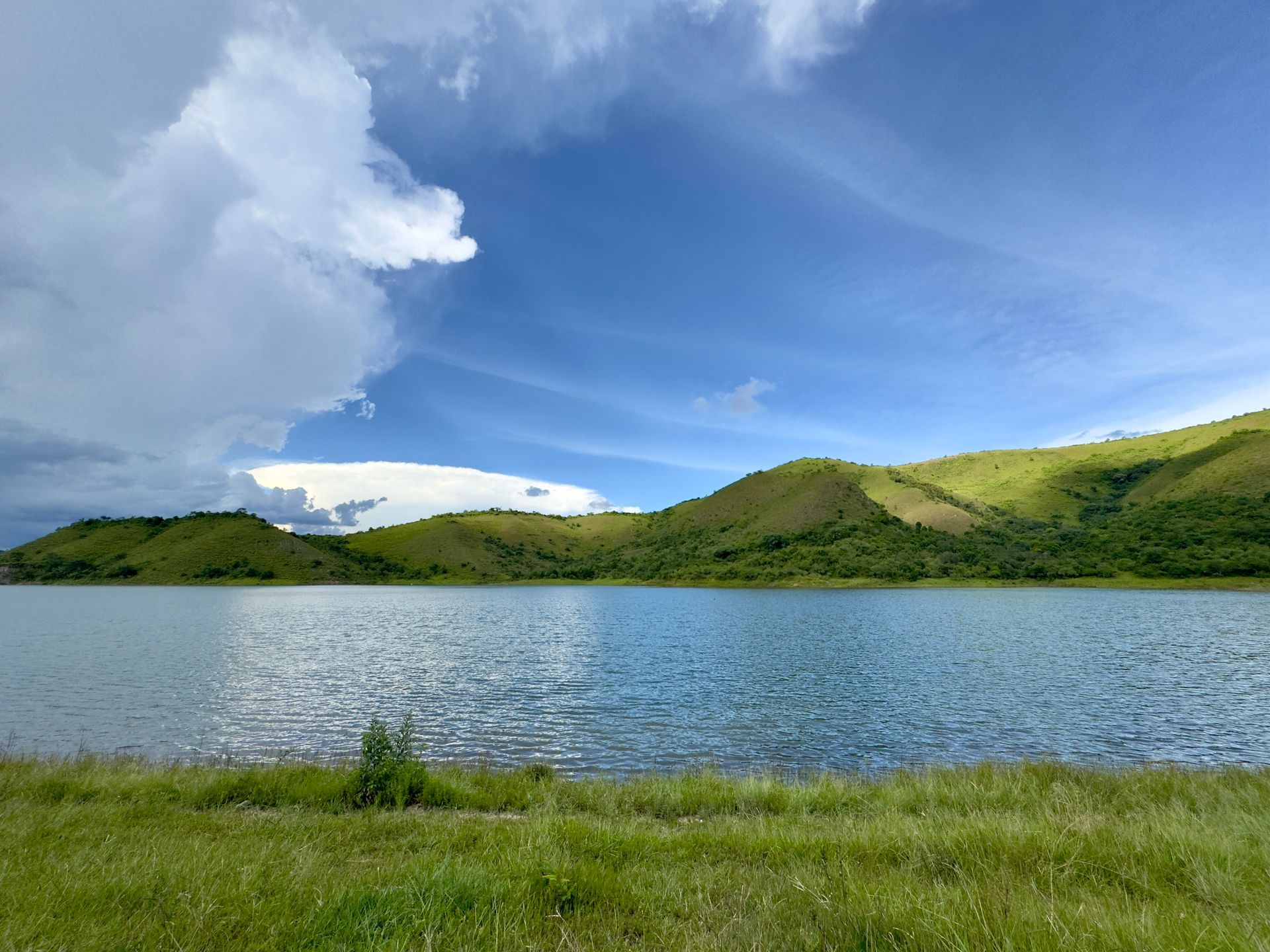 A lake with mountains in the background and a blue sky with clouds