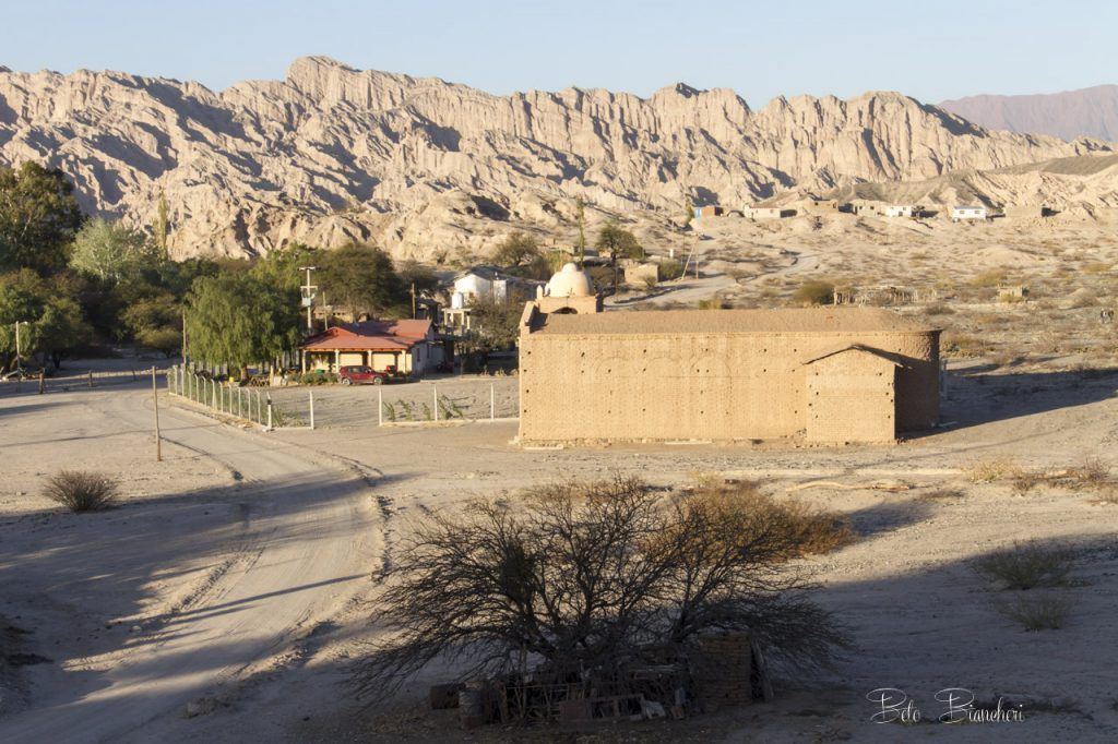 A desert landscape with a building in the foreground and mountains in the background