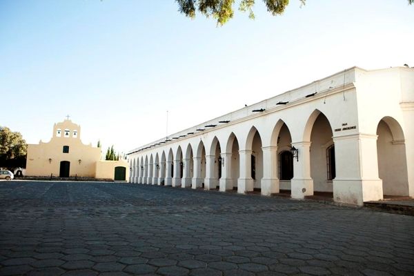 A white building with arches and a church in the background
