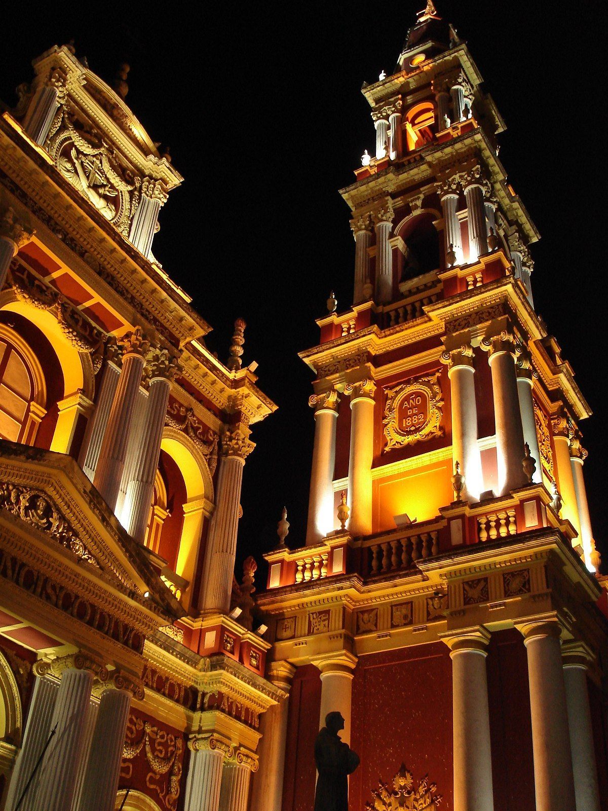 A large building with a clock tower lit up at night