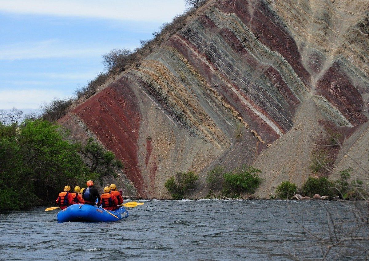 A group of people are rafting down a river with a mountain in the background.