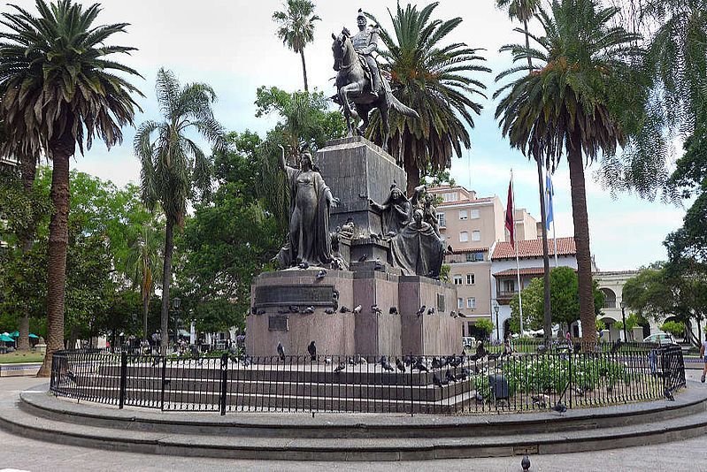A statue of a man on a horse in a park surrounded by palm trees