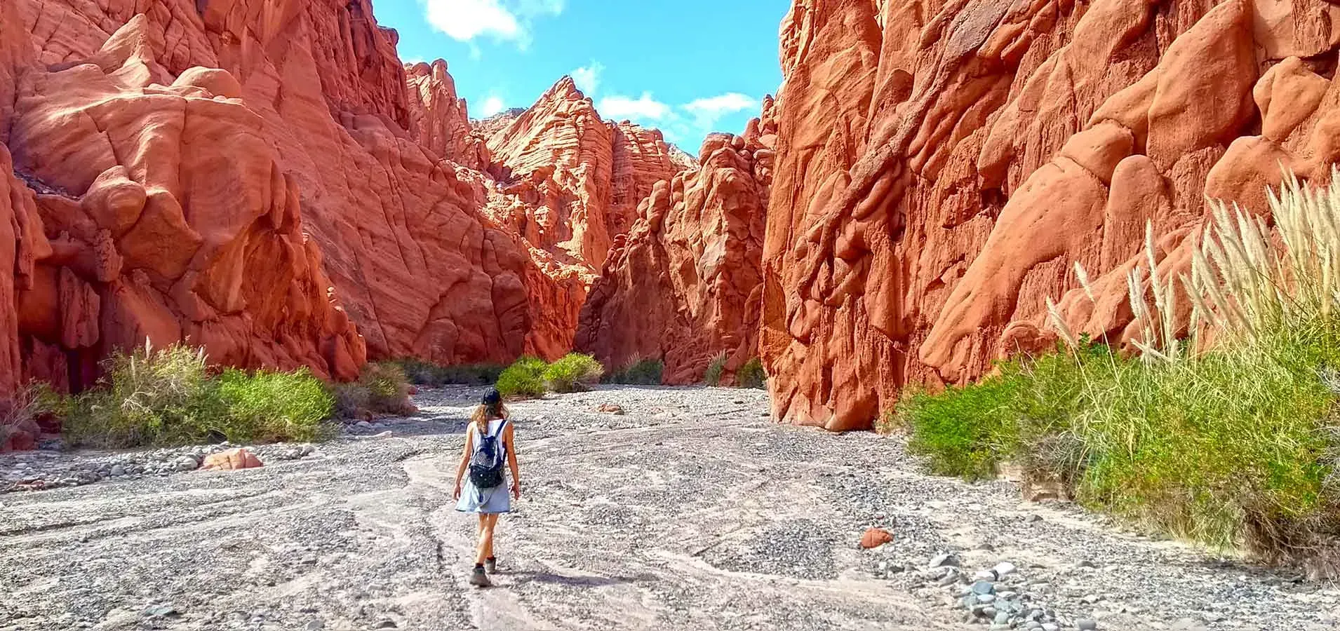 A person is walking through a canyon in the desert.