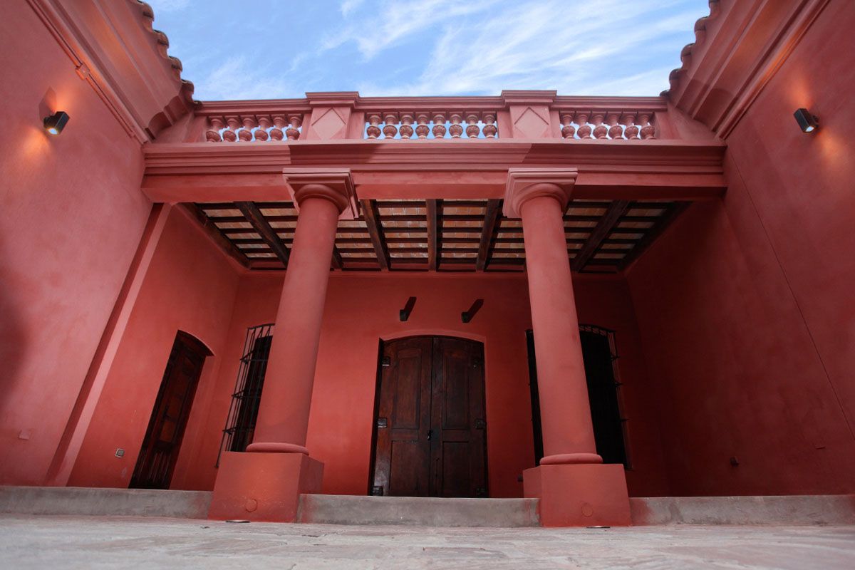 A red building with a balcony and columns