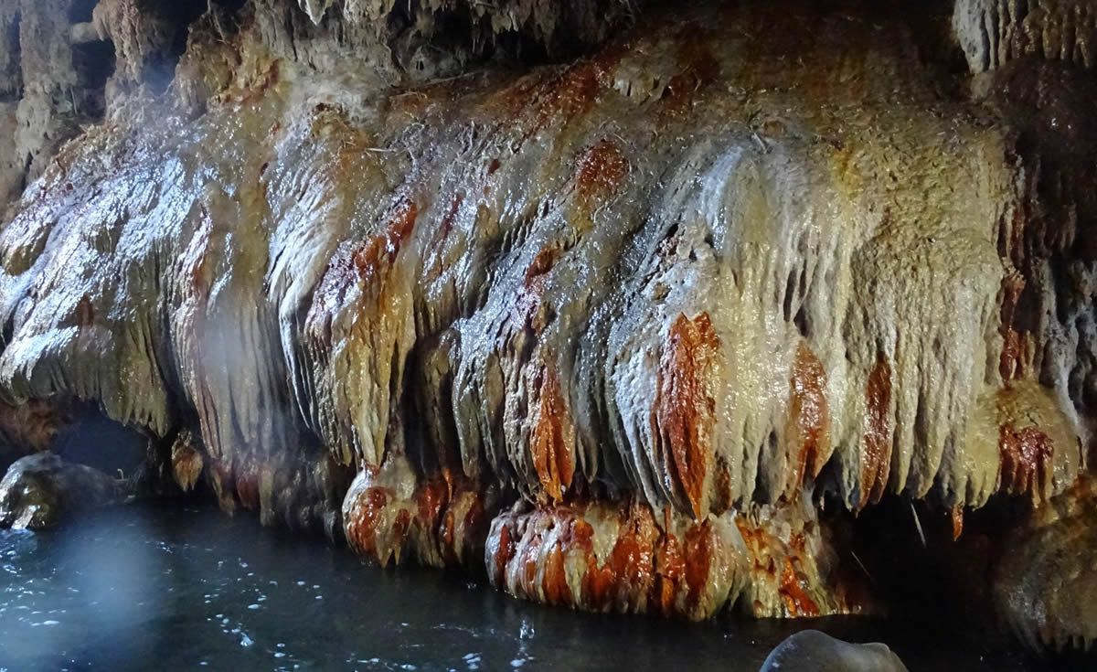 A large rock formation in a cave with water coming out of it.