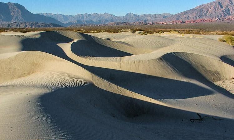Sand dunes in the desert with mountains in the background