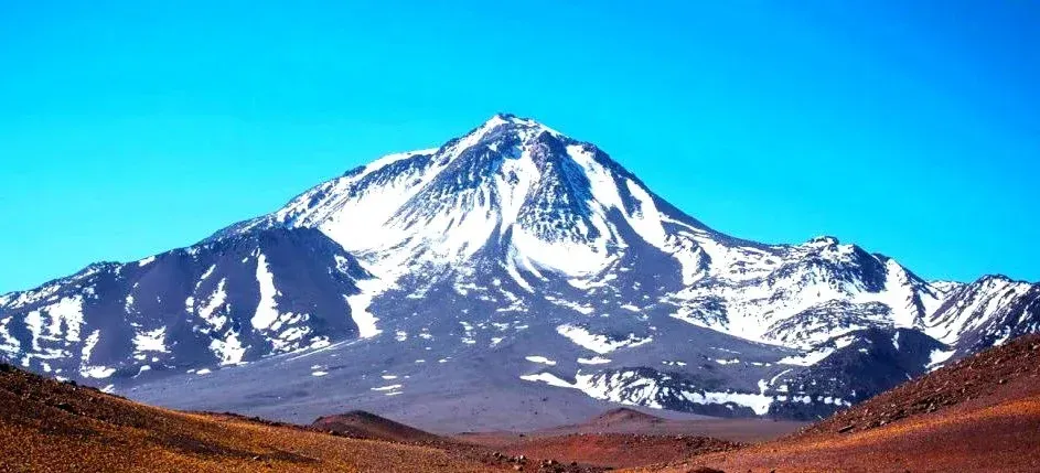 A snowy mountain with a blue sky in the background