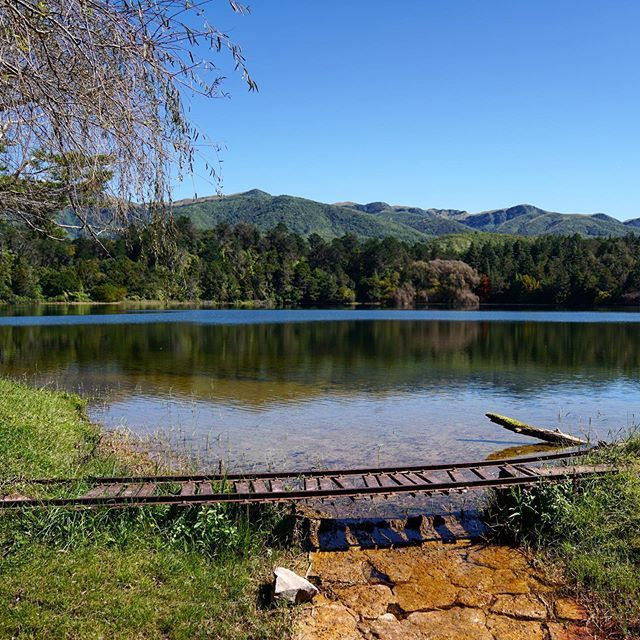A wooden bridge over a lake with mountains in the background