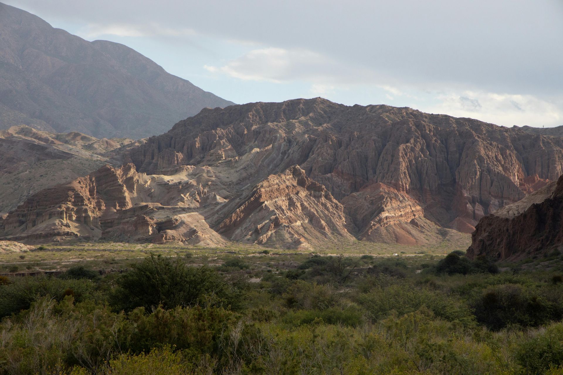 A valley with mountains in the background and trees in the foreground