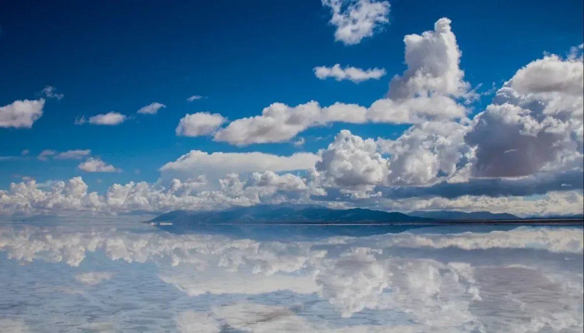 A blue sky with white clouds reflected in the water.