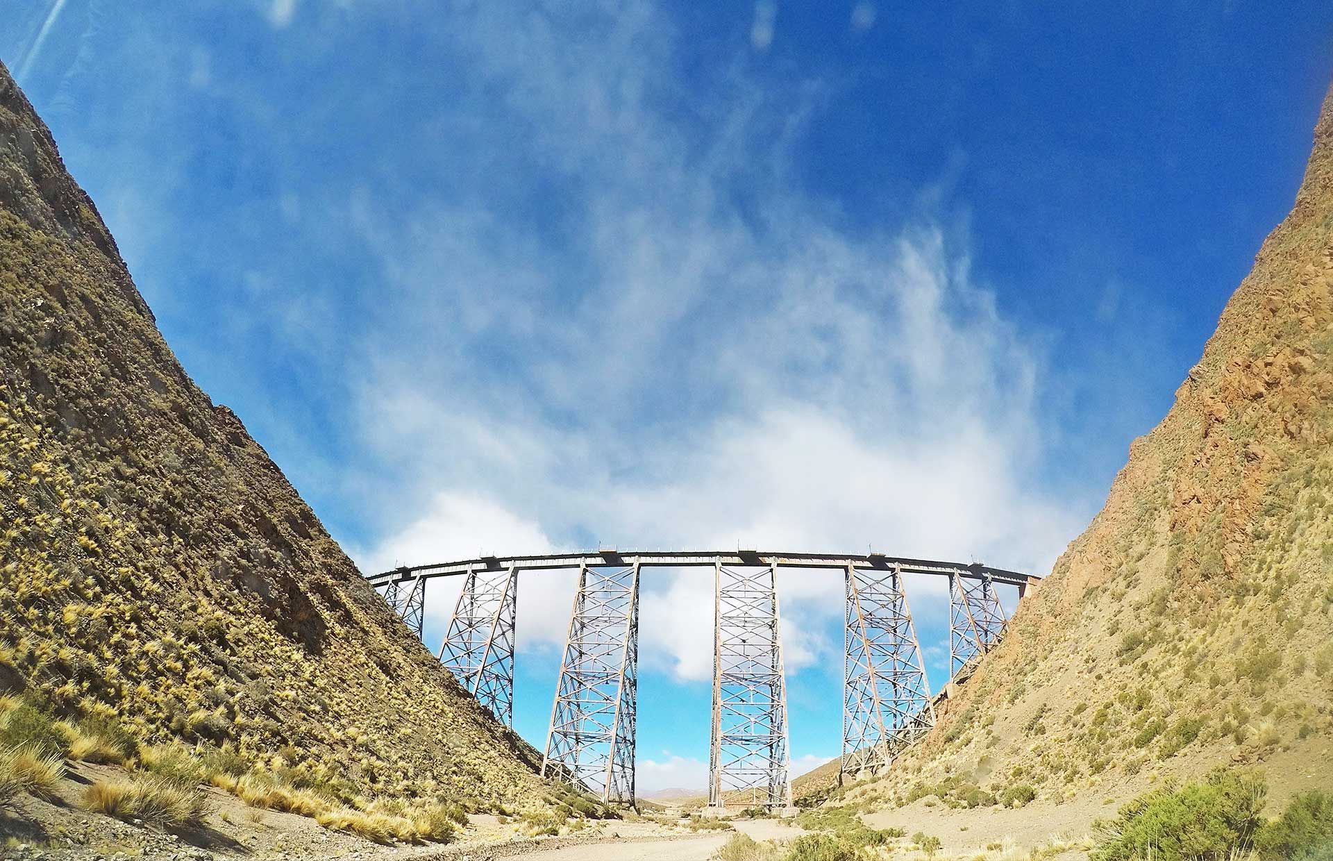 A bridge in the middle of a canyon with a blue sky in the background
