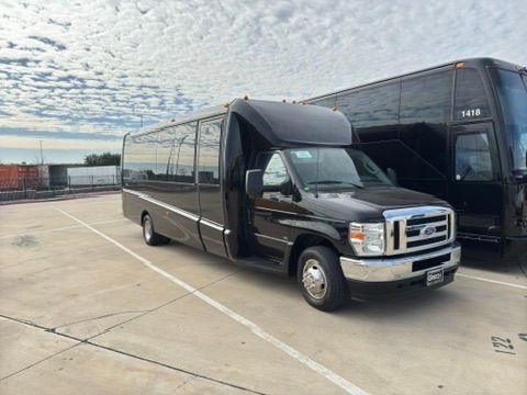 A black van is parked in a parking lot next to a bus.