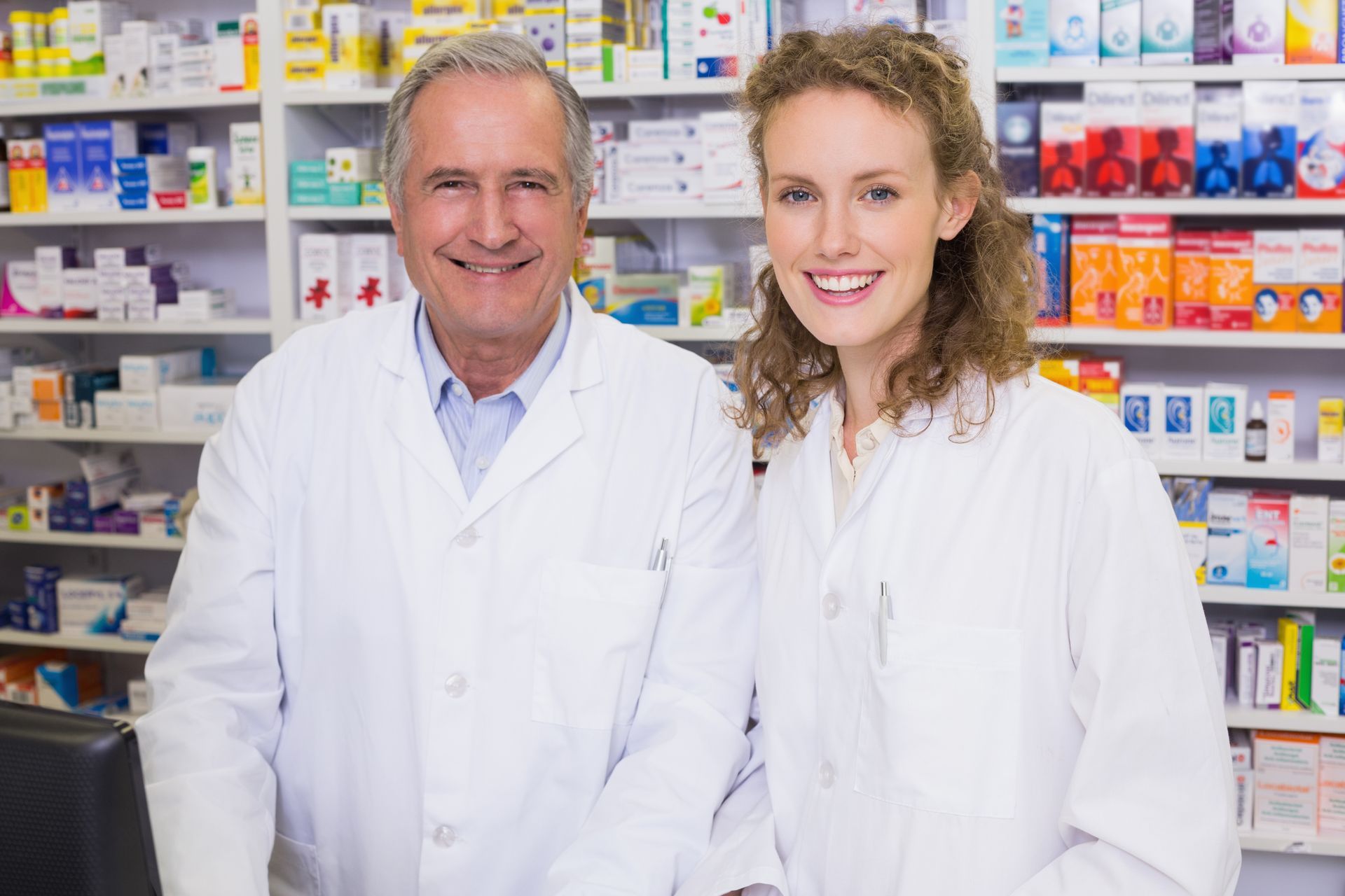 Two pharmacists smiling and looking at the camera