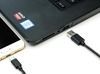 A cell phone is being charged by a laptop.